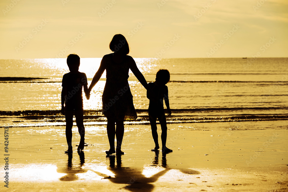 Silhouette boy mother walk on the beach