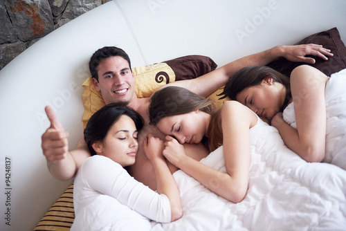handsome man in bed with three beautiful woman