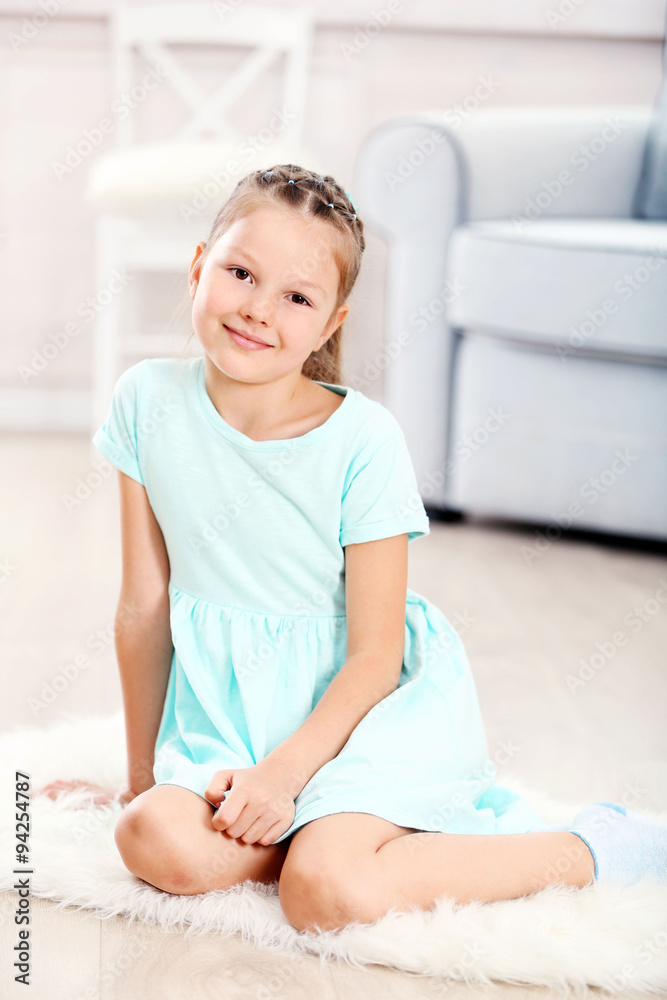 Little cute girl sitting on carpet, on home interior background Little cute girl sitting on carpet, on home interior background