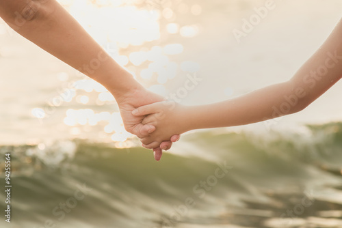 Hands of mother and son holding each other