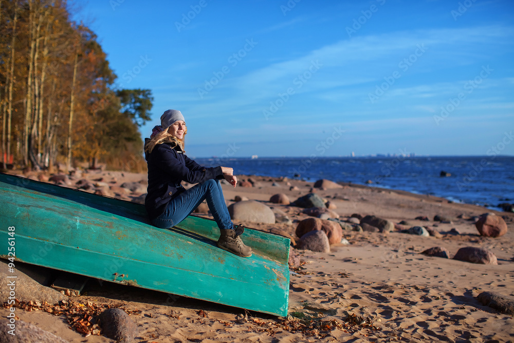 girl sitting on a boat in the autumn beach