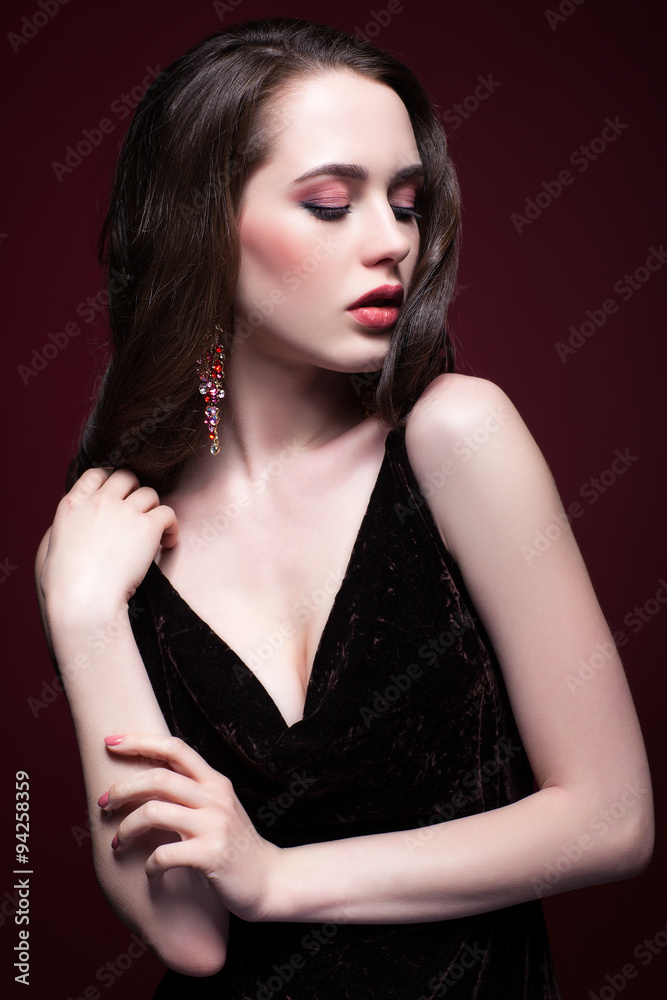 Naklejka premium Young beautiful woman in black dress on red marsala background