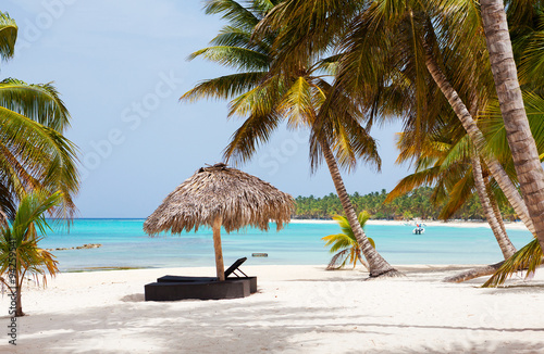 Beach parasol on the white sand beach with cloudy blue sky and sun
