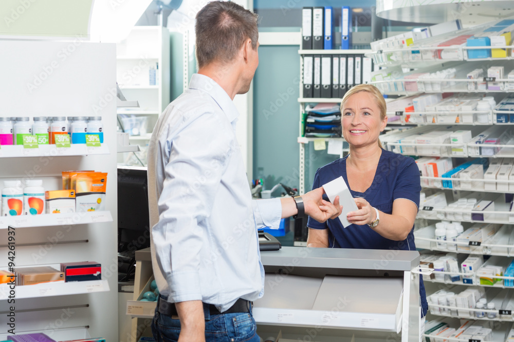 Chemist Giving Product To Customer In Pharmacy