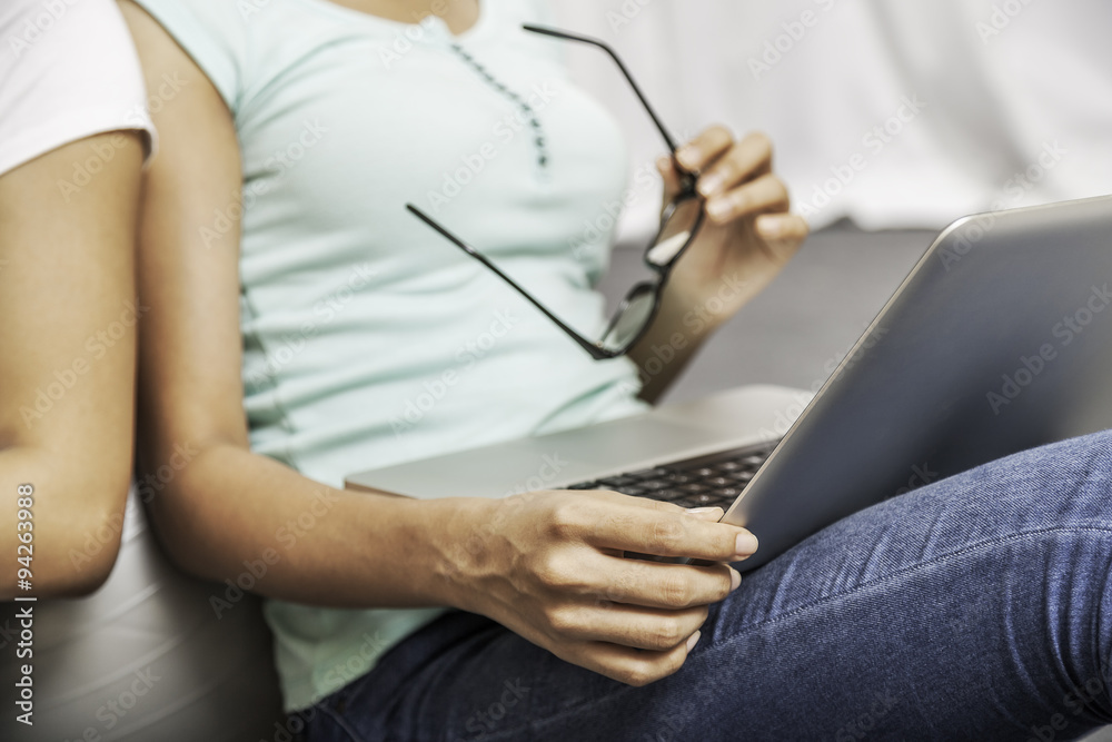 college student working on her laptop while holding glasses