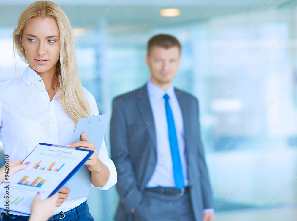 Businesswoman standing in office , holding documents in hand Businesswoman standing in office , holding documents in hand