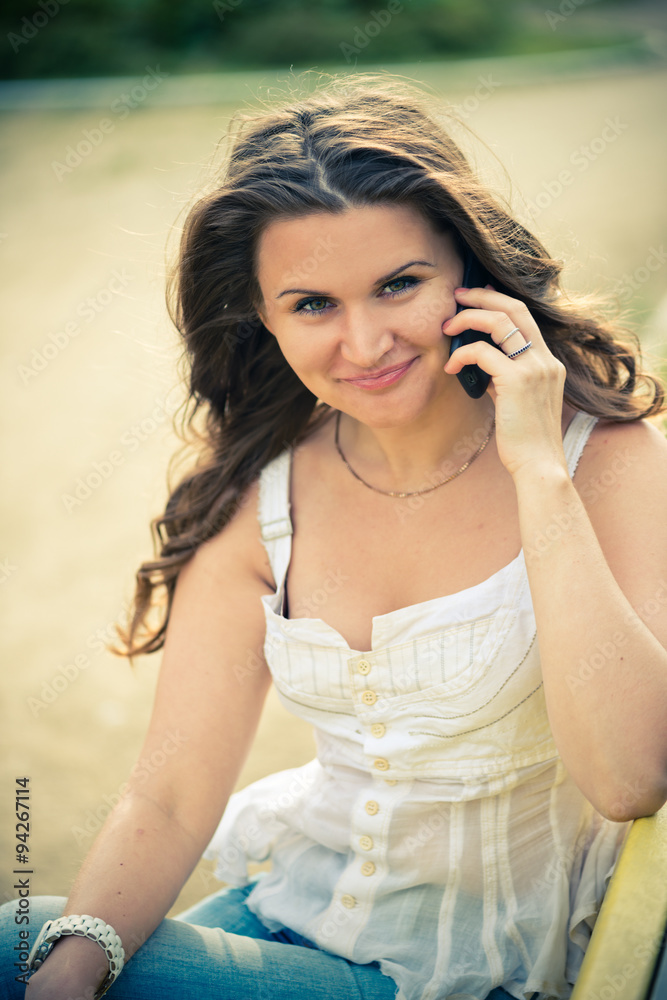 Fototapeta premium Outdoor portrait of young woman with phone