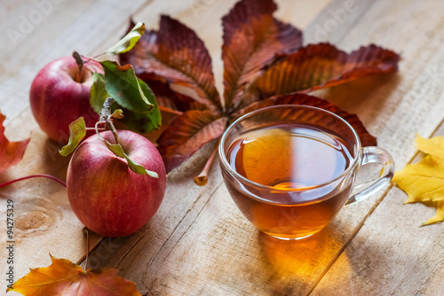 glass hot cup of tea on a wooden table with autumn leaves and ap