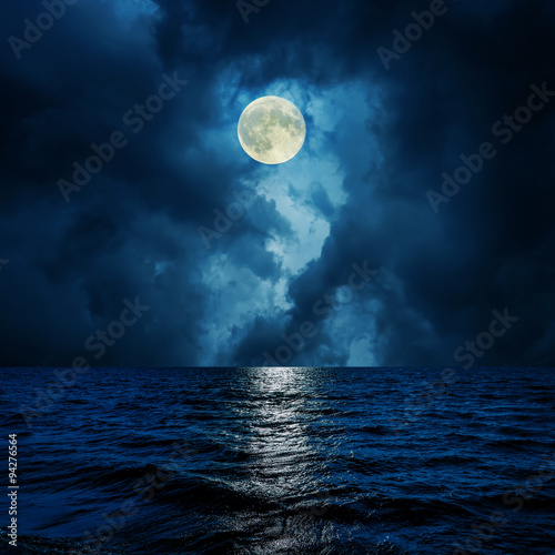 super moon in clouds over water