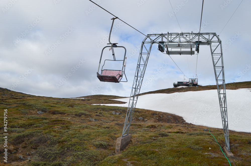 Ski lift on a mountain slope with snow patches