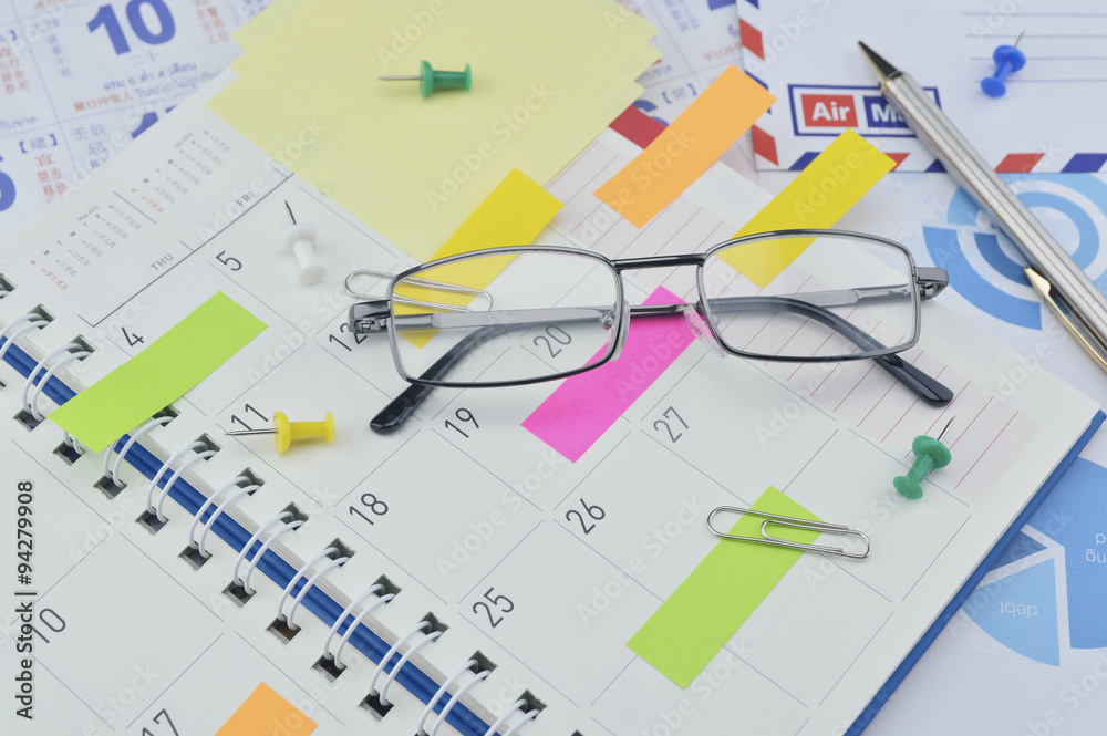 Glasses with colorful sticky notes and pen on diary page Glasses with colorful sticky notes and pen on diary page