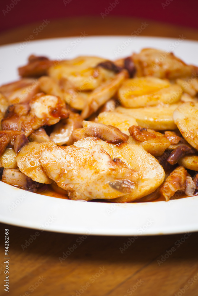 Octopus with paprika and potatoes on a white plate, also known a