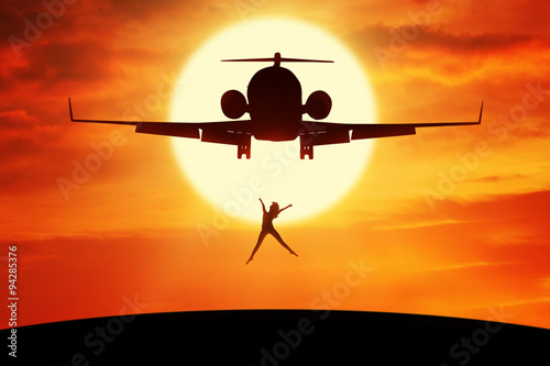 Happy woman leaps on the hill under airplane