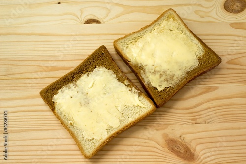 Toasts with butter on wooden background
