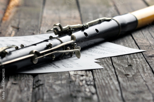 Old black flute and music notes on rusty wooden table