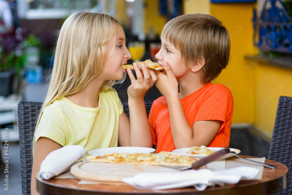 Happy children indoors eating pizza smiling Happy children indoors eating pizza smiling