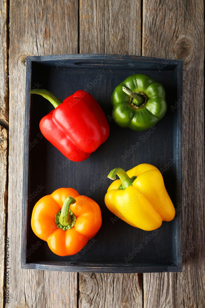 Four fresh pepper in blue tray on grey wooden background Four fresh pepper in blue tray on grey wooden background