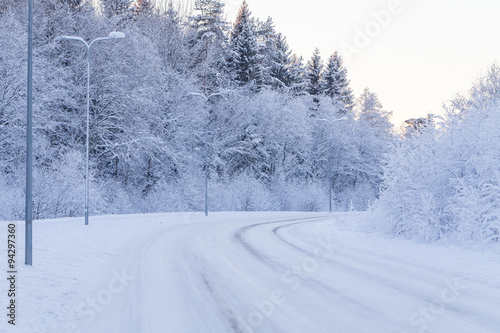 Winter evening forest with road covered with snow