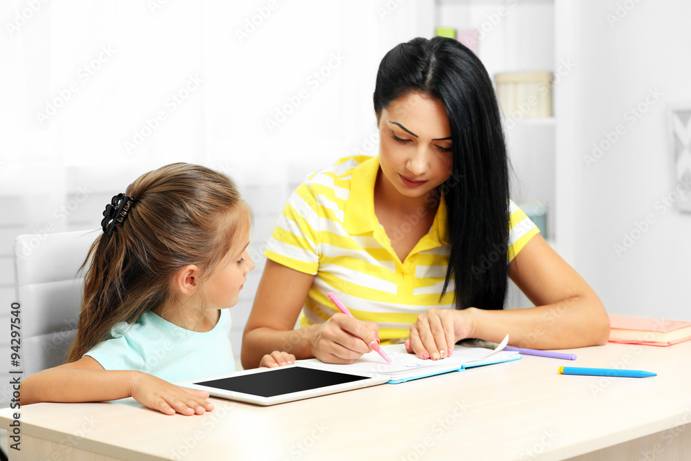 Beautiful school girl doing homework with mother at home Beautiful school girl doing homework with mother at home