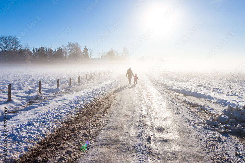 Naklejka premium Mother and child on foggy snow road
