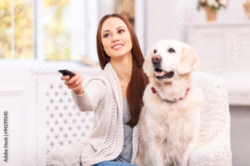 Fototapeta Naklejka Na Ścianę i Meble -  Young girl showing something to her dog on TV.