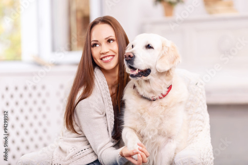 Lovely girl is smiling vividly while caressing a dog.