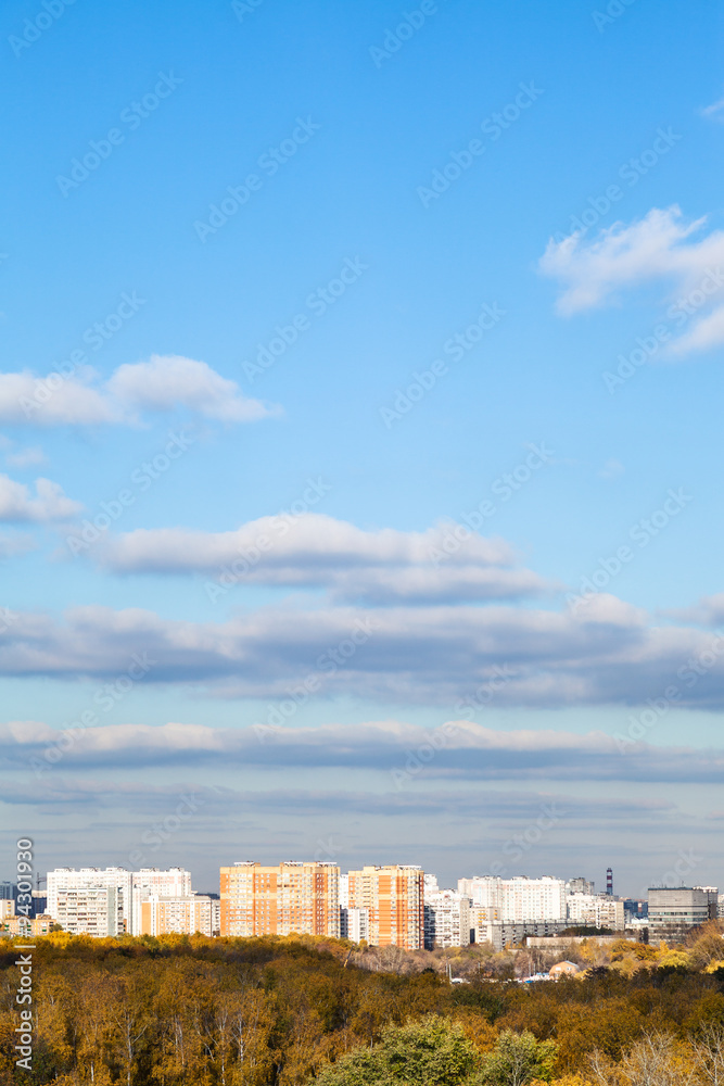 blue sky with clouds over city and woods in autumn