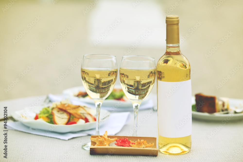 Bottle of luxury wine with tasty salad on white served table