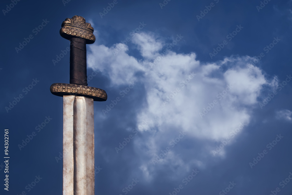 Medieval viking sword against a dramatic sky Medieval viking sword against a dramatic sky