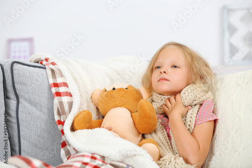 Little girl with sore throat holding toy bear closeup photo