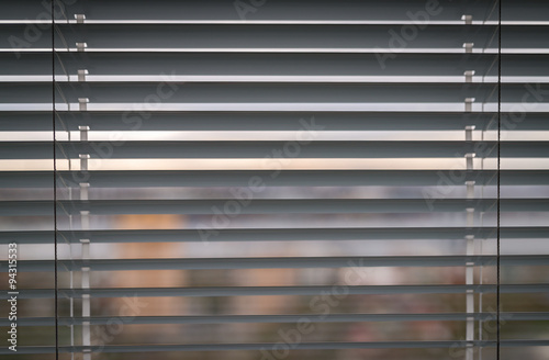White venetian blinds. Selective focus on the window handle.