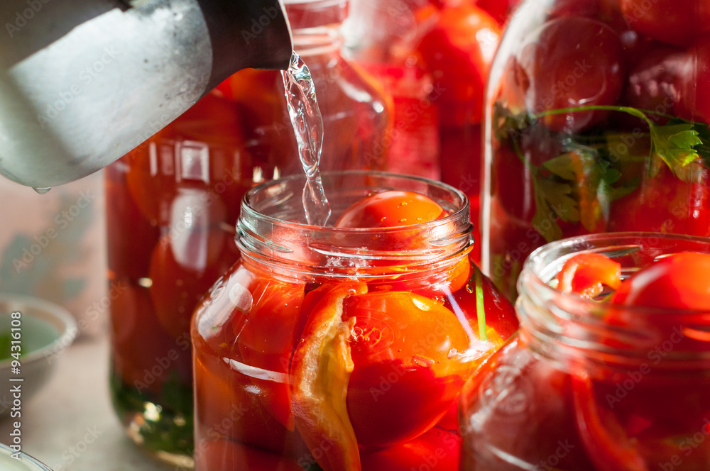 Canning process of tomato in mason jar. On background is few Canning process of tomato in mason jar. On background is few