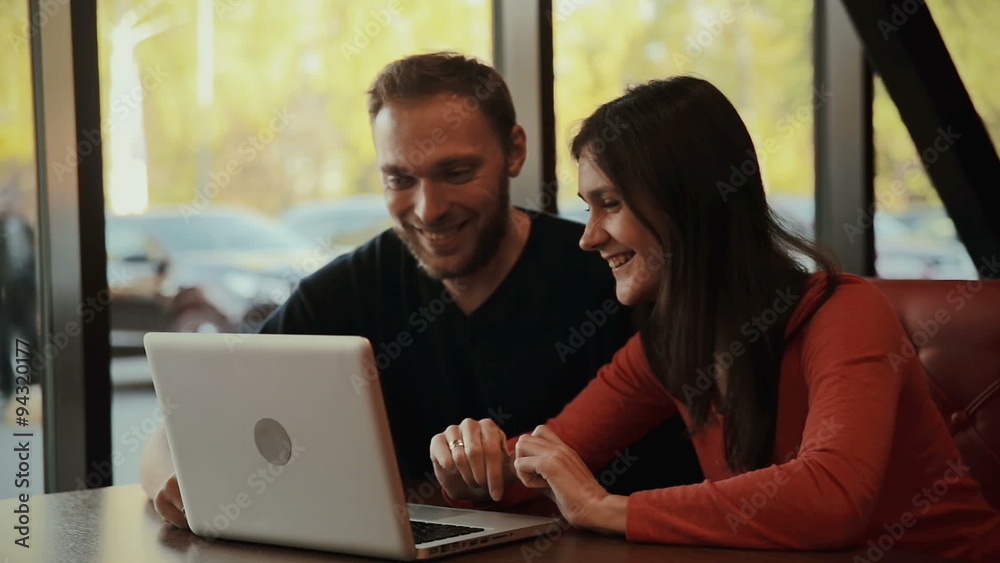 man and woman sitting at cafe with a laptop man and woman sitting at cafe with a laptop