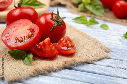 Fresh tomatoes with basil on wooden table close up