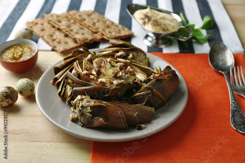 Roasted artichokes on plate, on color wooden background