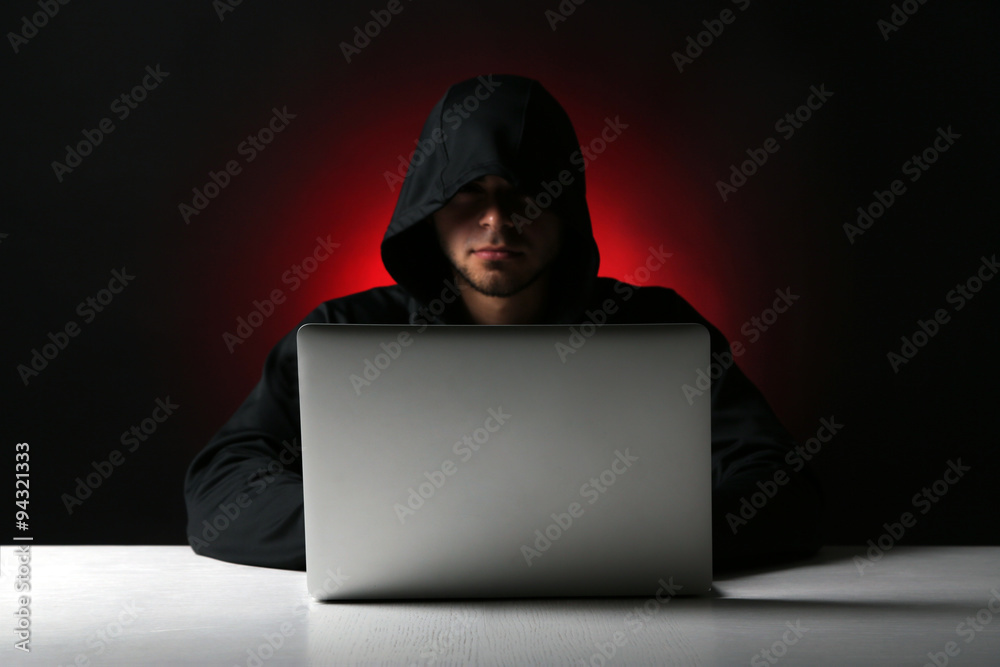 Hacker with computer and laptop on colorful dark background Hacker with computer and laptop on colorful dark background