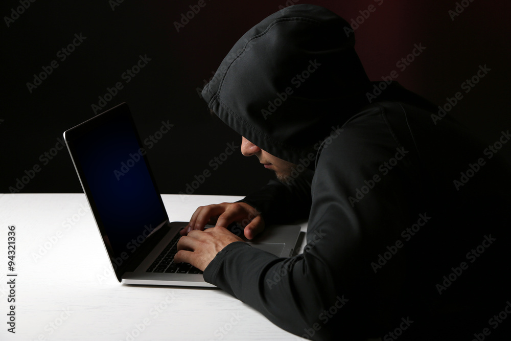 Hacker with computer and laptop on colorful dark background Hacker with computer and laptop on colorful dark background