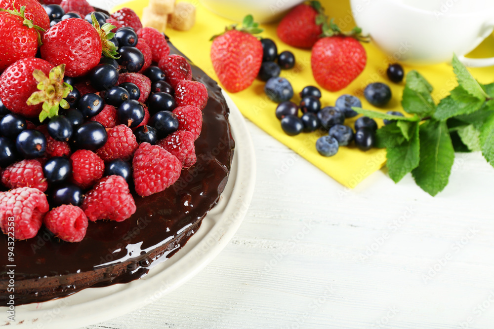 Delicious chocolate cake with summer berries on white wooden background Delicious chocolate cake with summer berries on white wooden background