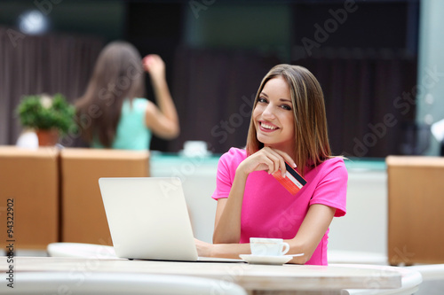 Beautiful young woman with laptop and credit card in cafe © Africa Studio