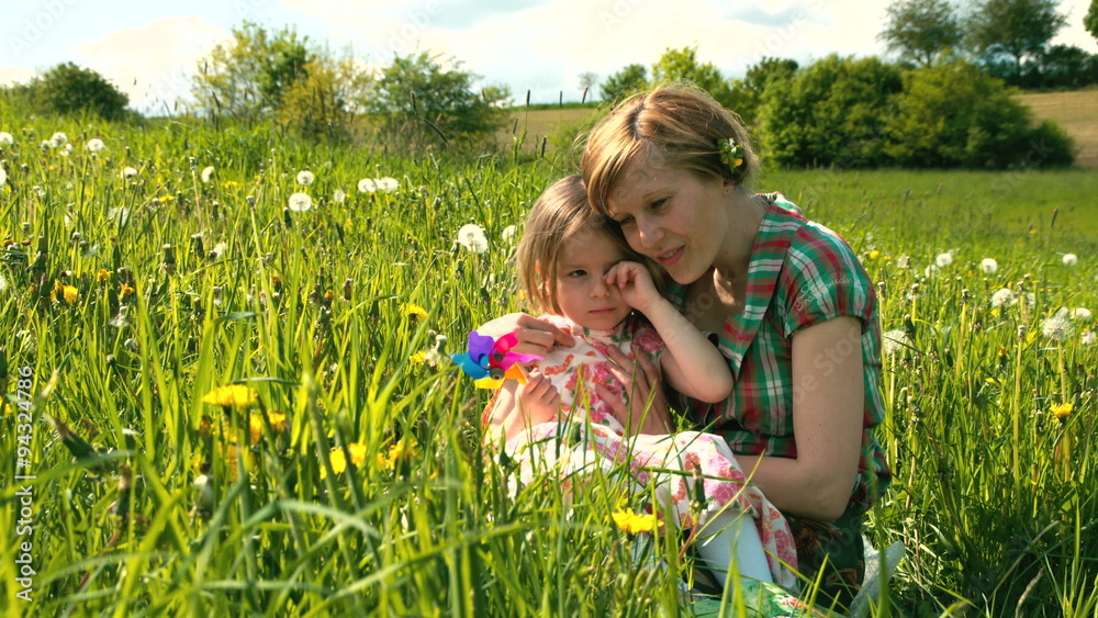 Die Mutter tröstet ihre Tochter auf einer Frühlingswiese Die Mutter tröstet ihre Tochter auf einer Frühlingswiese