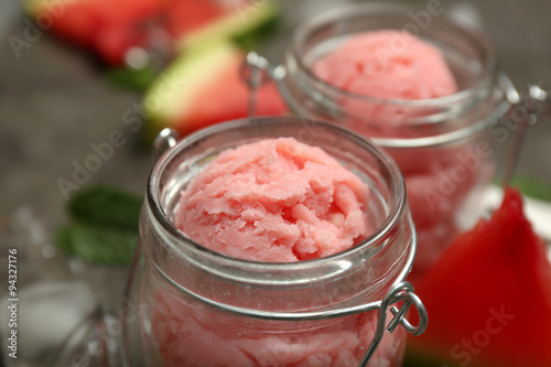 Watermelon ice cream in glass jars on dark background