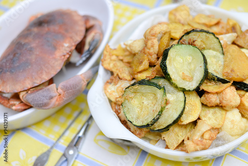 White dishes with crab and fried vegetables on rustic tablecloth