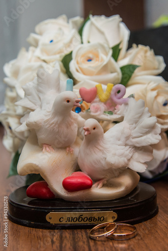 Two wedding rings lie the table.Figurine doves.Love. photo