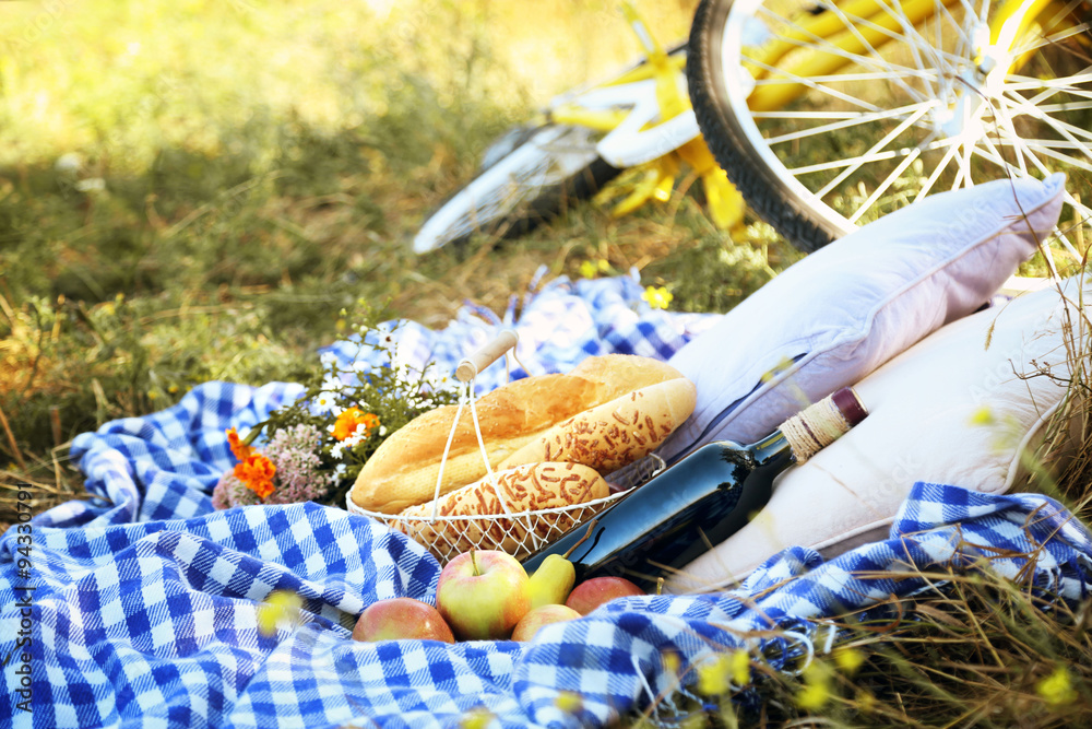 Fototapeta premium Old yellow bicycle and picnic snack on checkered blanket on grass in park
