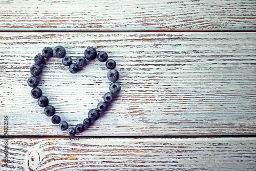 Heart shaped bilberries on old wooden background