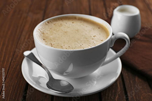 Cup of coffee with cream on brown napkin