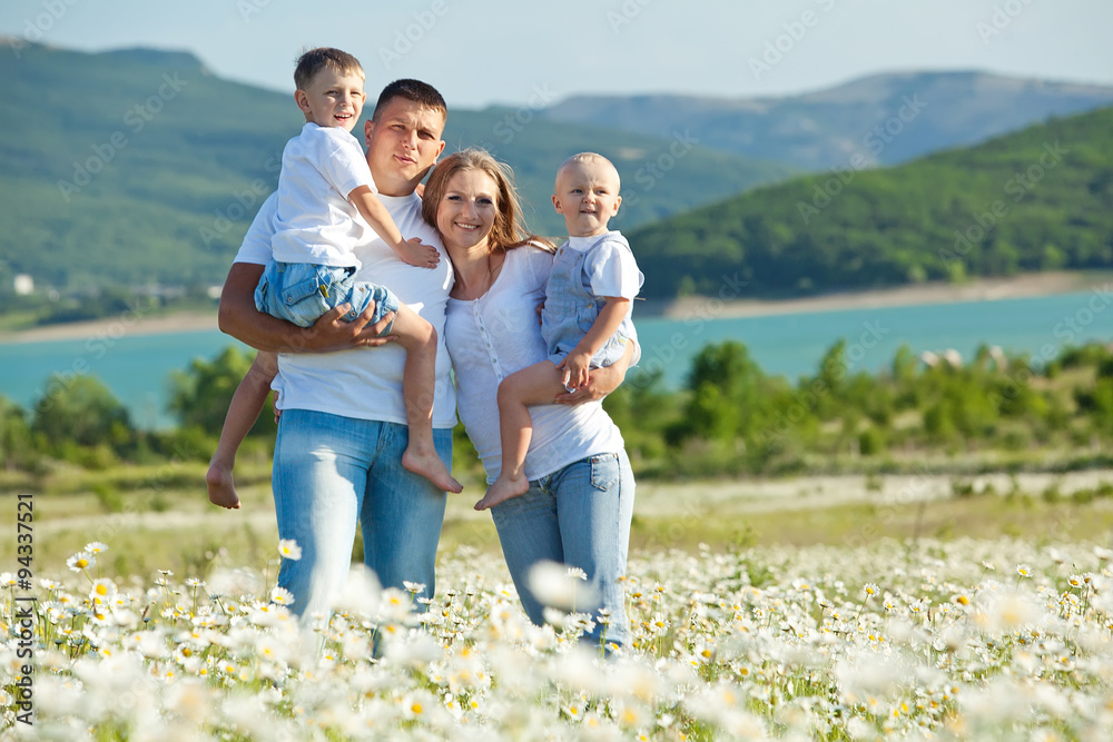 Happy family are walking in camomile field 