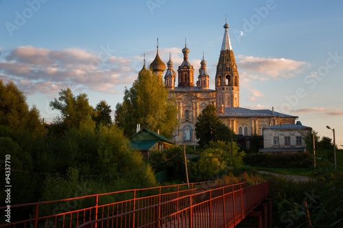 Rural evening landscape with the bridge and old stone church, Russia