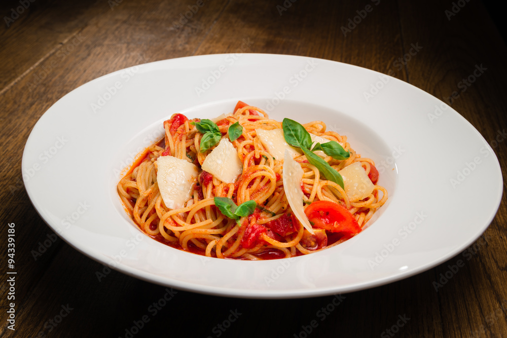 Spaghetti with tomato, parmesan and basil served in a white plate Spaghetti with tomato, parmesan and basil served in a white plate