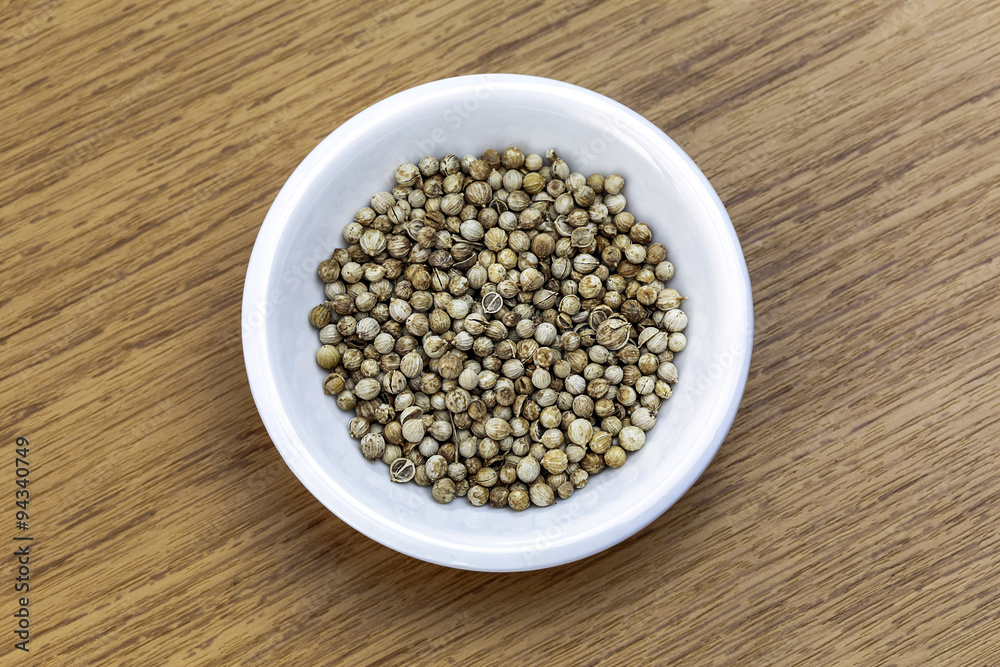 Dry coriander in white bowl on wooden table Dry coriander in white bowl on wooden table